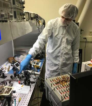 Joe Thomes in cleanroom working at optical test bench